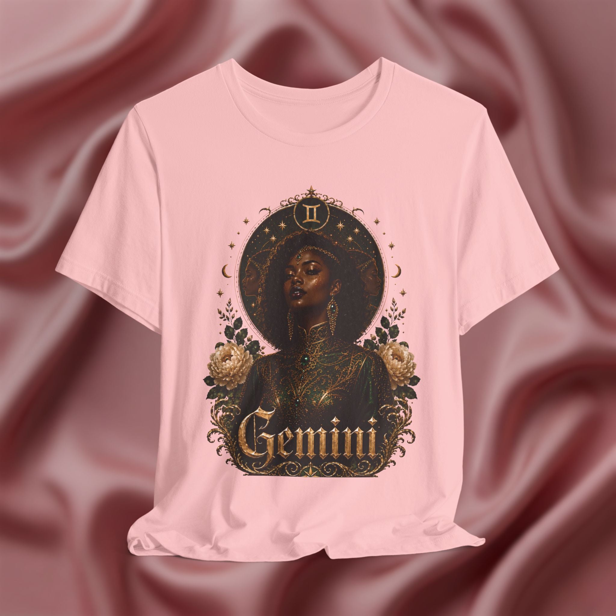 Pink t-shirt with a graphic design of a woman, flowers, and the word 'Gemini' on a pink fabric background.