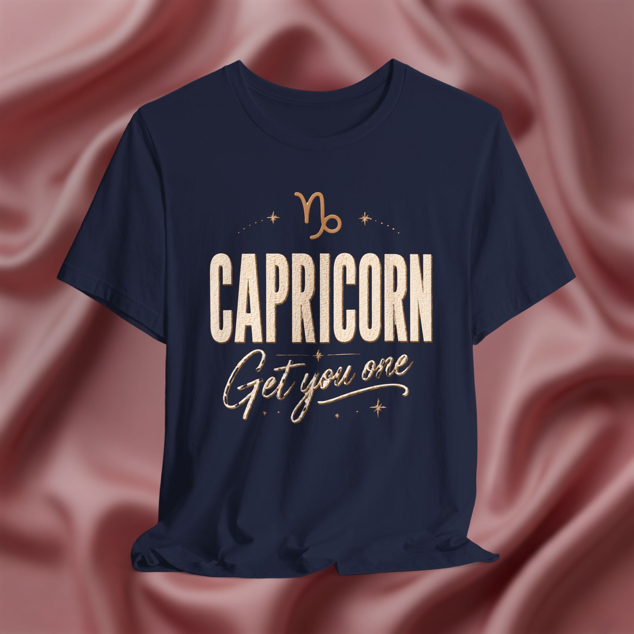 Navy t-shirt with 'Capricorn Get you one' text on a pink fabric background