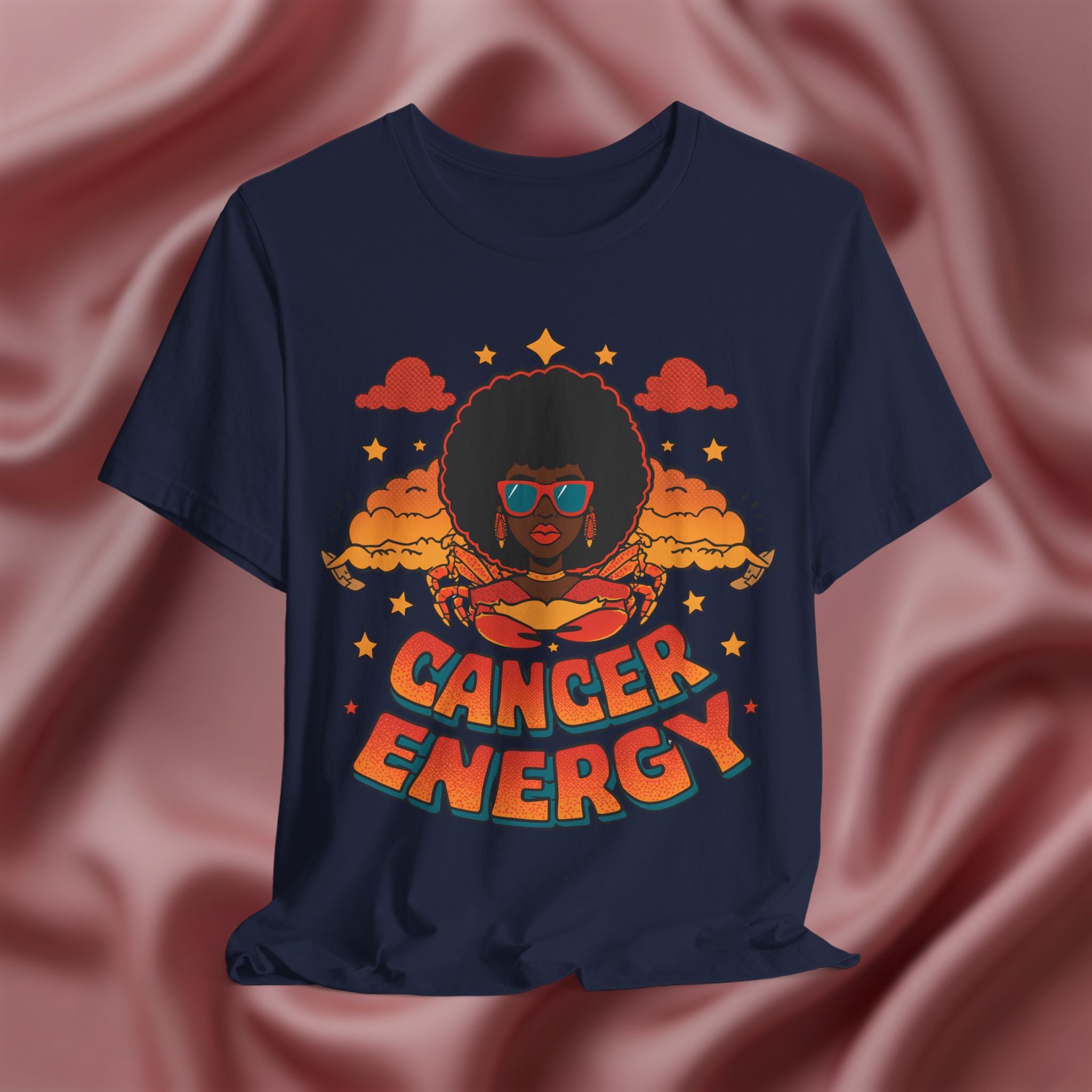 Navy blue t-shirt with a graphic design of a person with an afro and 'Cancer Energy' text on a pink fabric background.