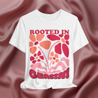 White t-shirt with floral design and text 'Rooted in Gemini' on a maroon fabric background