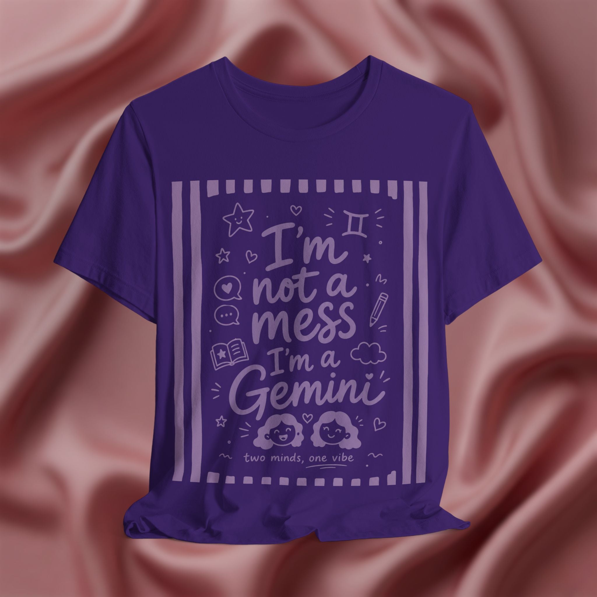 Purple t-shirt with purple text 'I'm not a mess I'm a Gemini and graphics on a pink fabric background