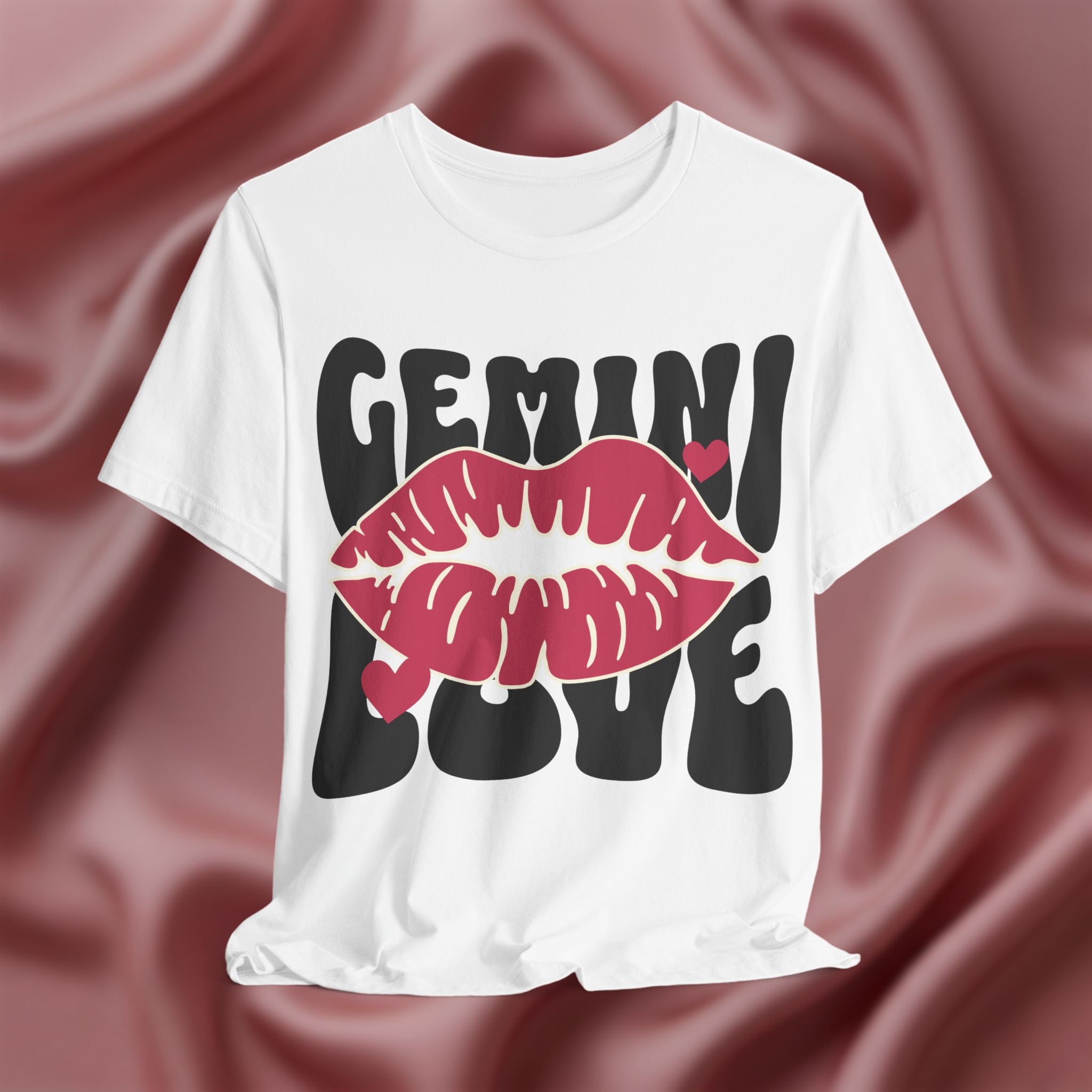 White t-shirt with 'GEMINI LOVE' design on a maroon fabric background
