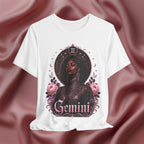 White t-shirt with 'Gemini' design featuring a black woman, flowers, and astrological symbols on a maroon fabric background.
