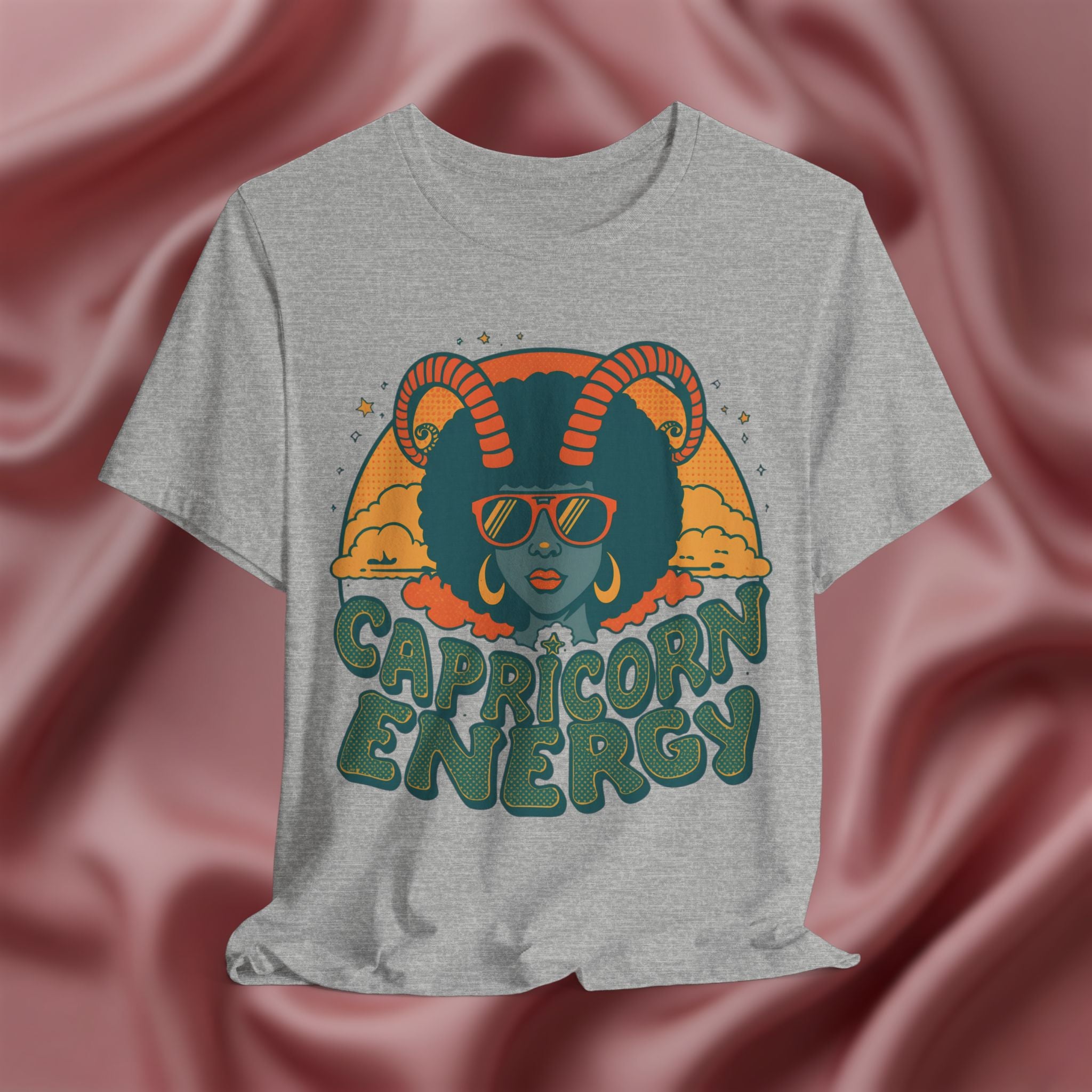 Gray t-shirt with Capricorn Energy design on a pink fabric background