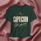 Green t-shirt with 'Capricorn Get you one' text on a pink fabric background