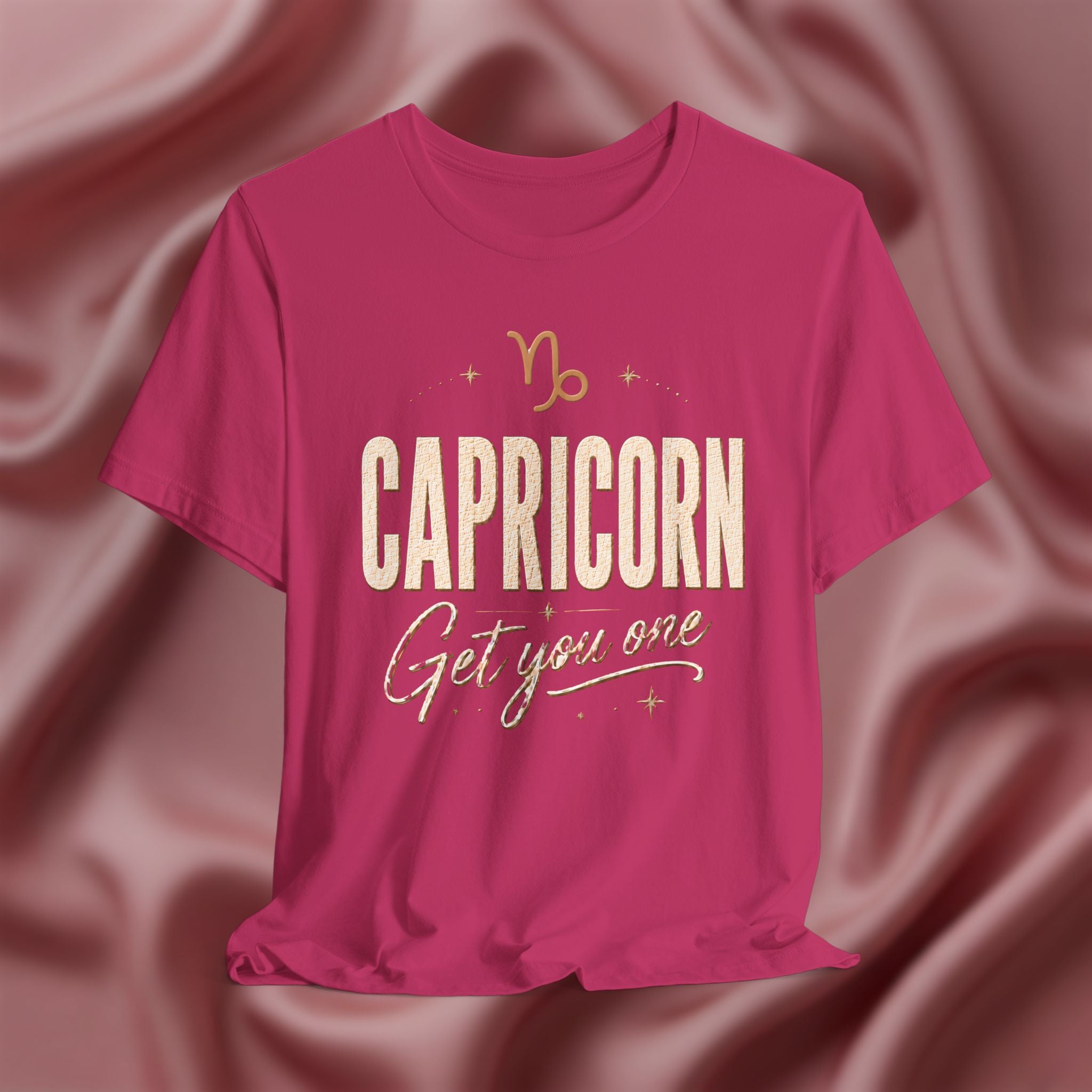 Pink t-shirt with 'Capricorn Get you one' text on a pink fabric background