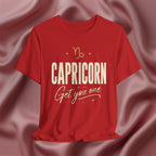 Red t-shirt with 'Capricorn Get you one' text on a pink fabric background