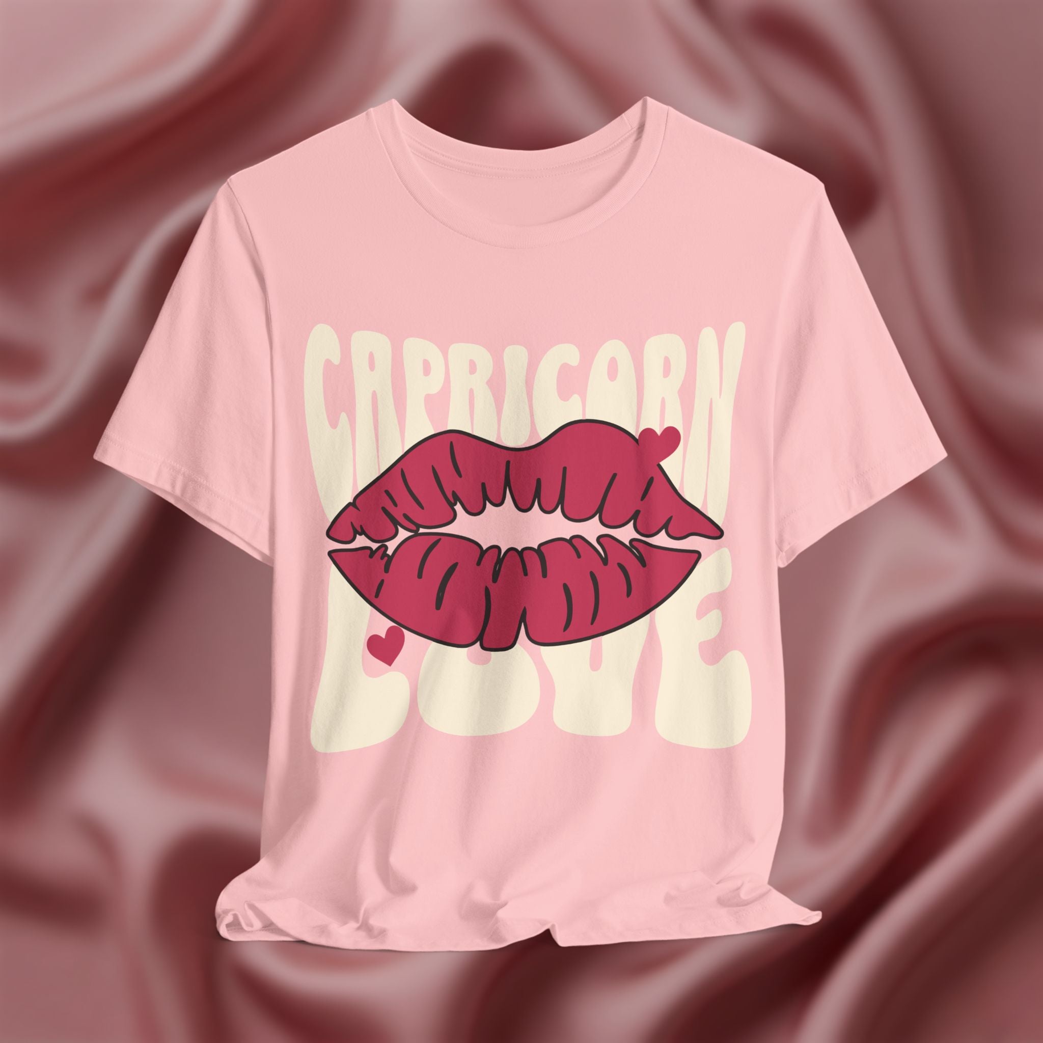 Pink t-shirt with 'Capricorn Love'  with hearts and lips graphic on a pink fabric background