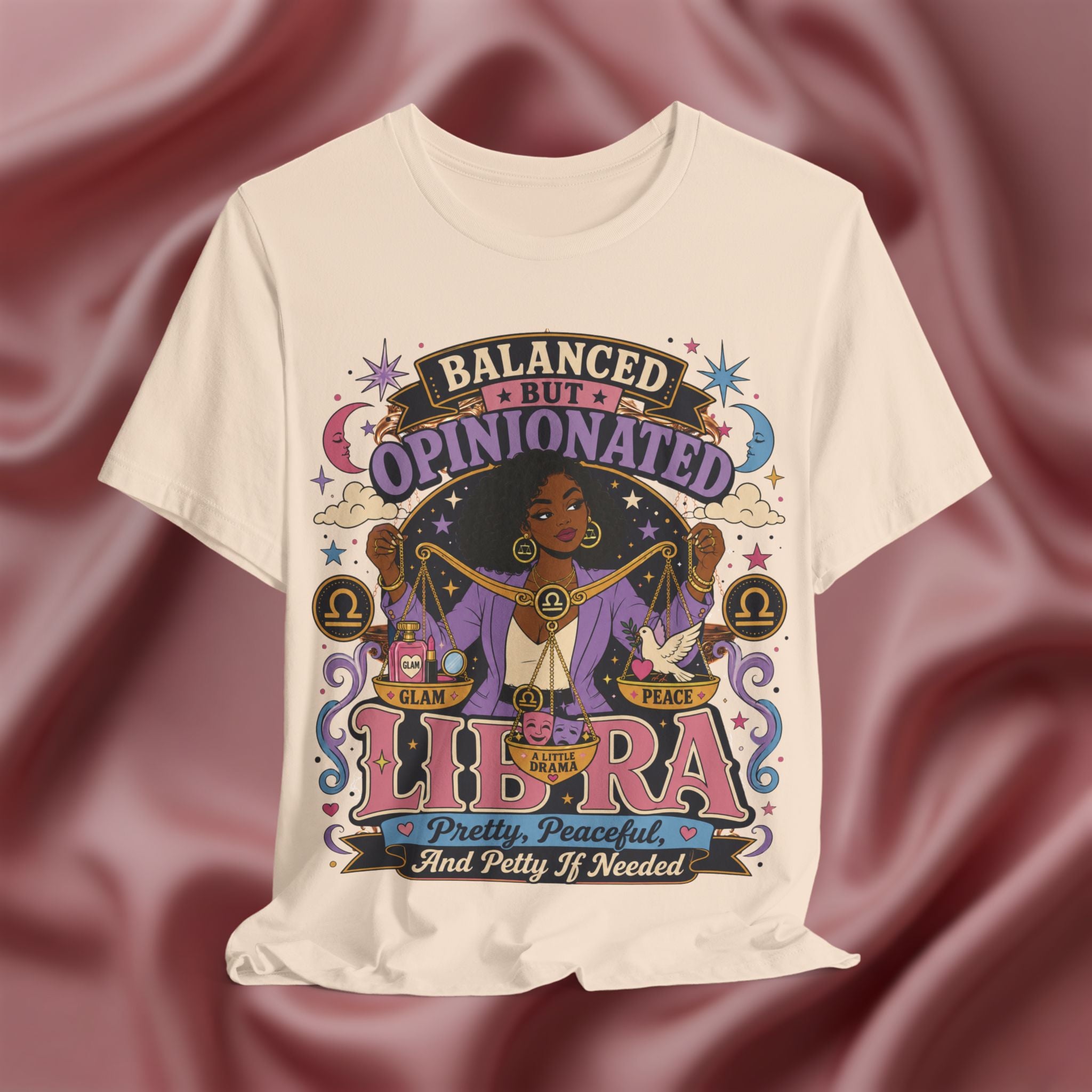 Soft cream T-shirt with Libra zodiac design on a maroon fabric background