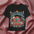 Black t-shirt with Cancer zodiac design on a pink fabric background