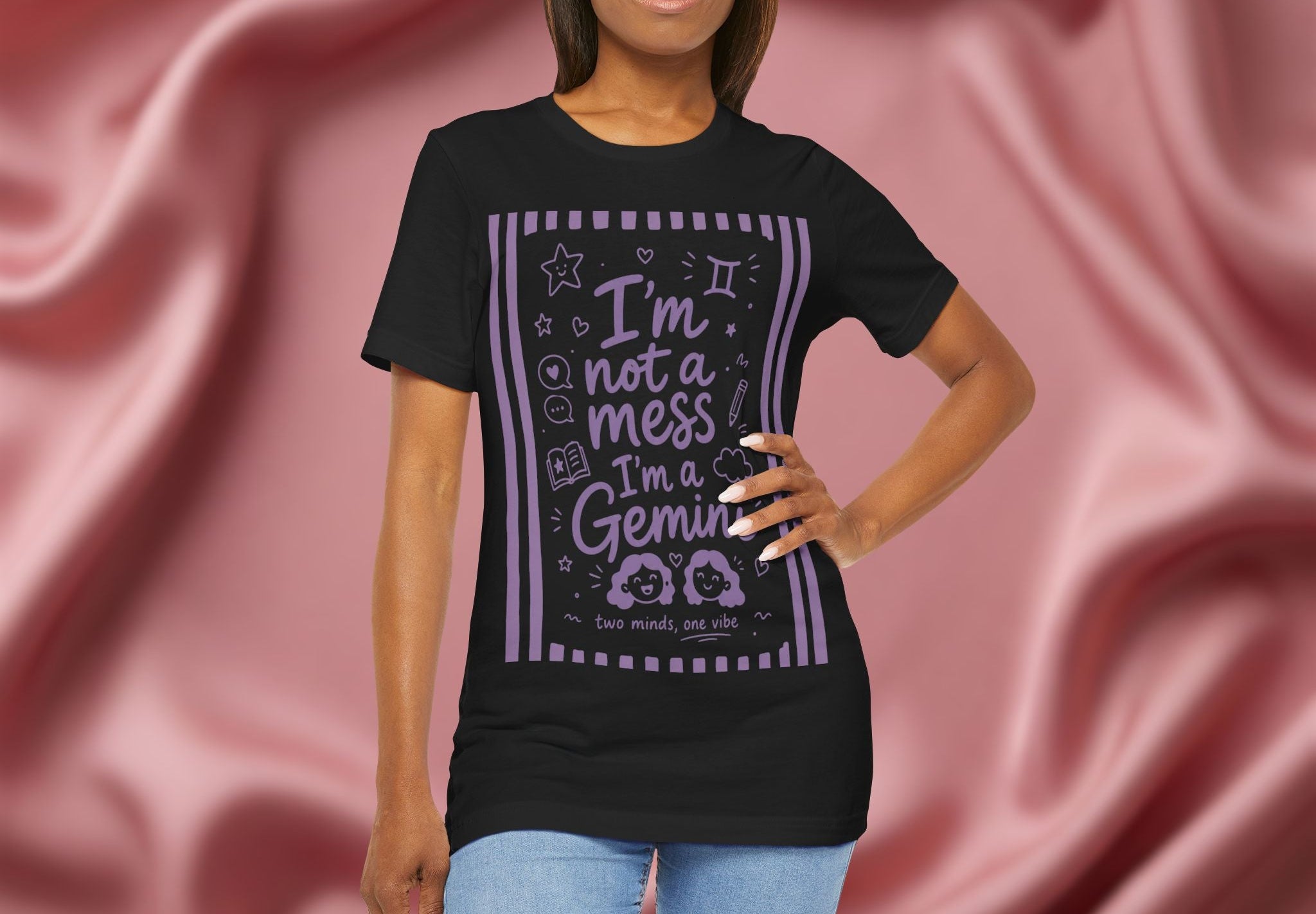 Woman wearing a black t-shirt with purple text 'I'm not a mess I'm a Gemini and graphics on a pink fabric background