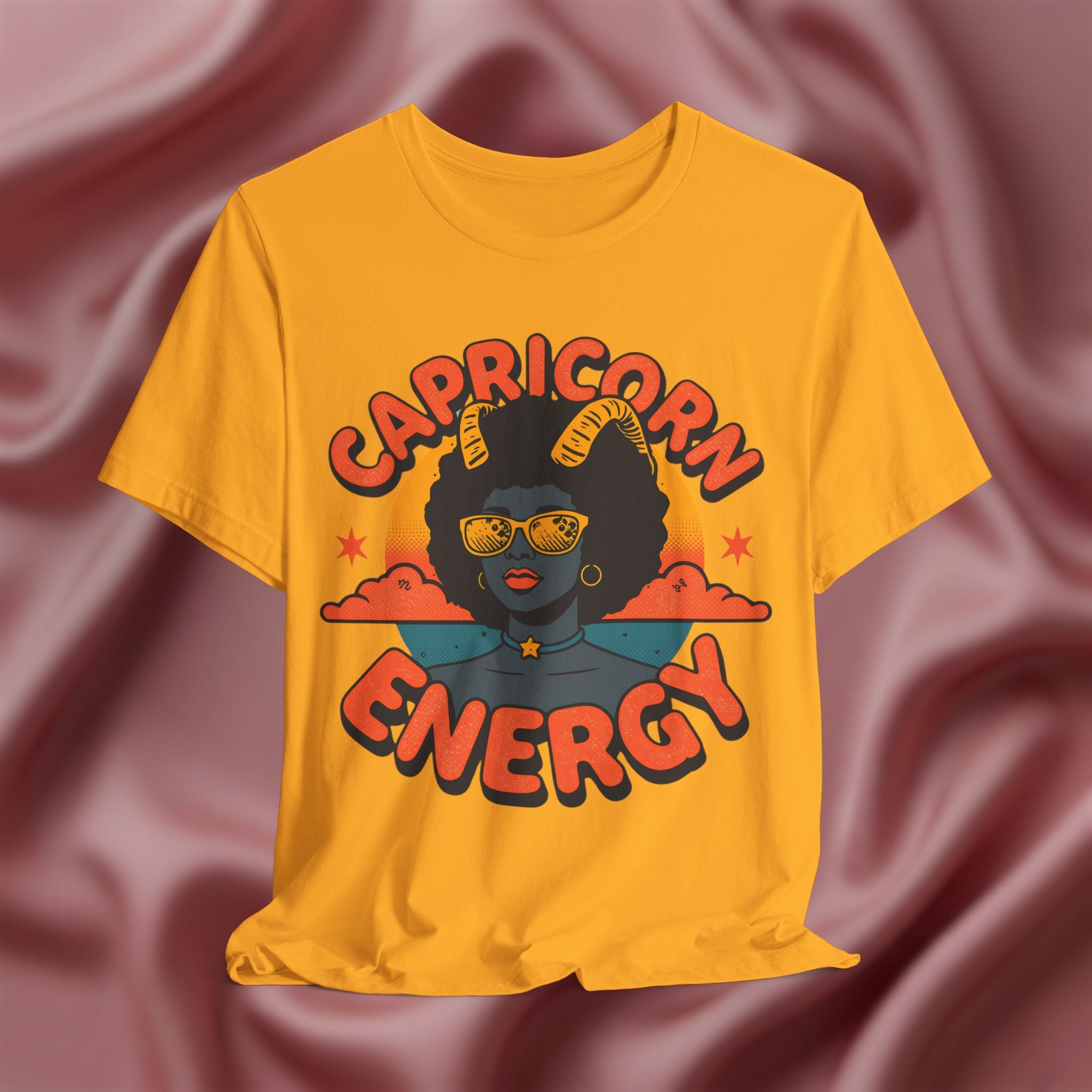 Yellow t-shirt with 'Capricorn Energy' design on a maroon fabric background