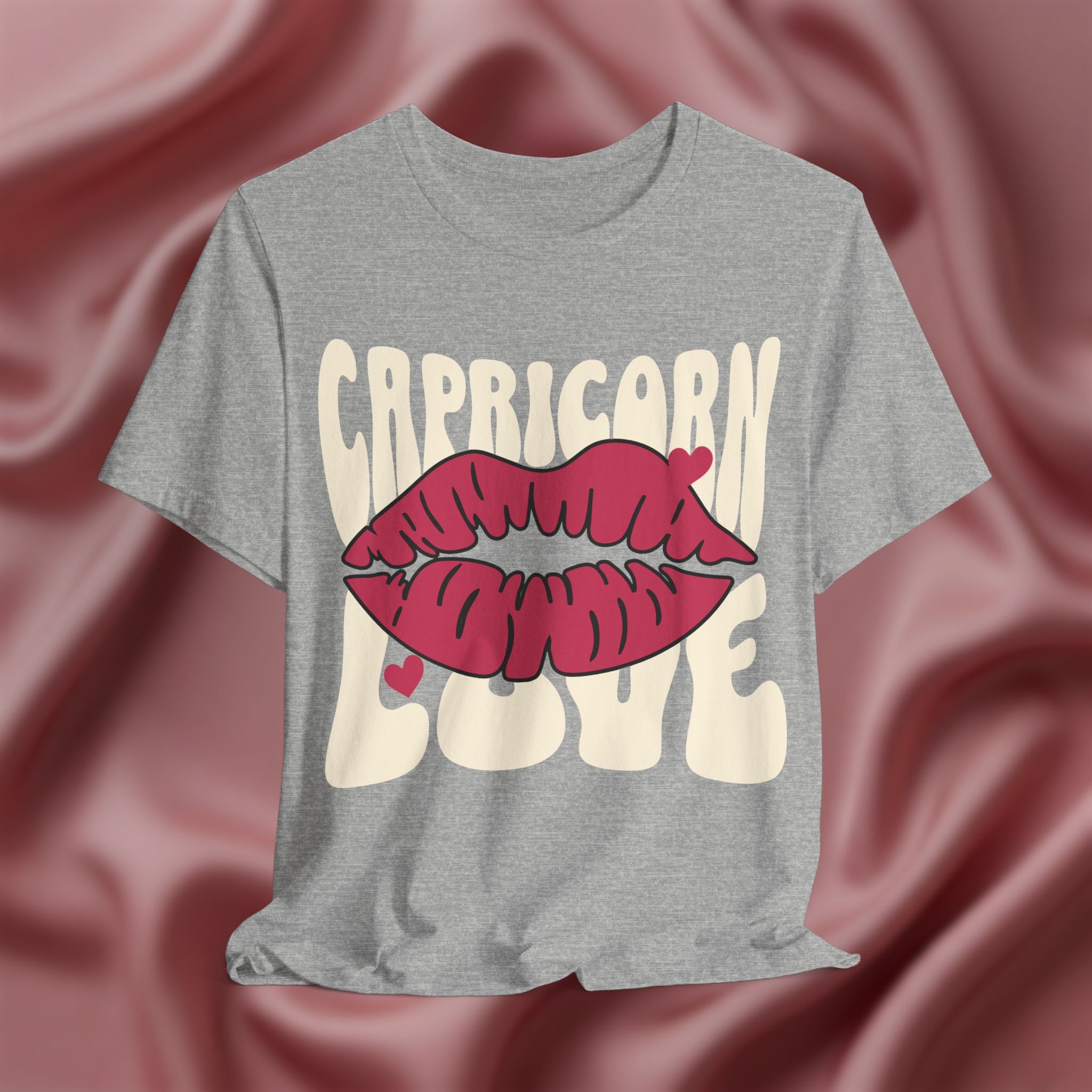 Gray t-shirt with 'Capricorn Love'  with hearts and lips graphic on a pink fabric background