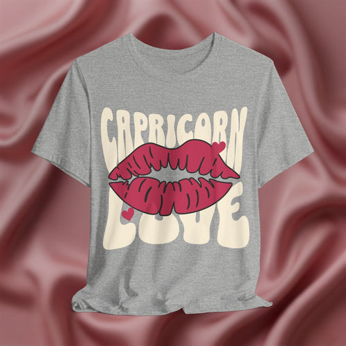 Gray t-shirt with 'Capricorn Love'  with hearts and lips graphic on a pink fabric background