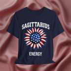 Navy blue t-shirt with American flag sunflower and 'SAGITTARIUS ENERGY' text on a textured pink background