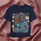 Navy blue t-shirt with Aquarius-themed design featuring a person with braided hair and a creature on a pink fabric background.