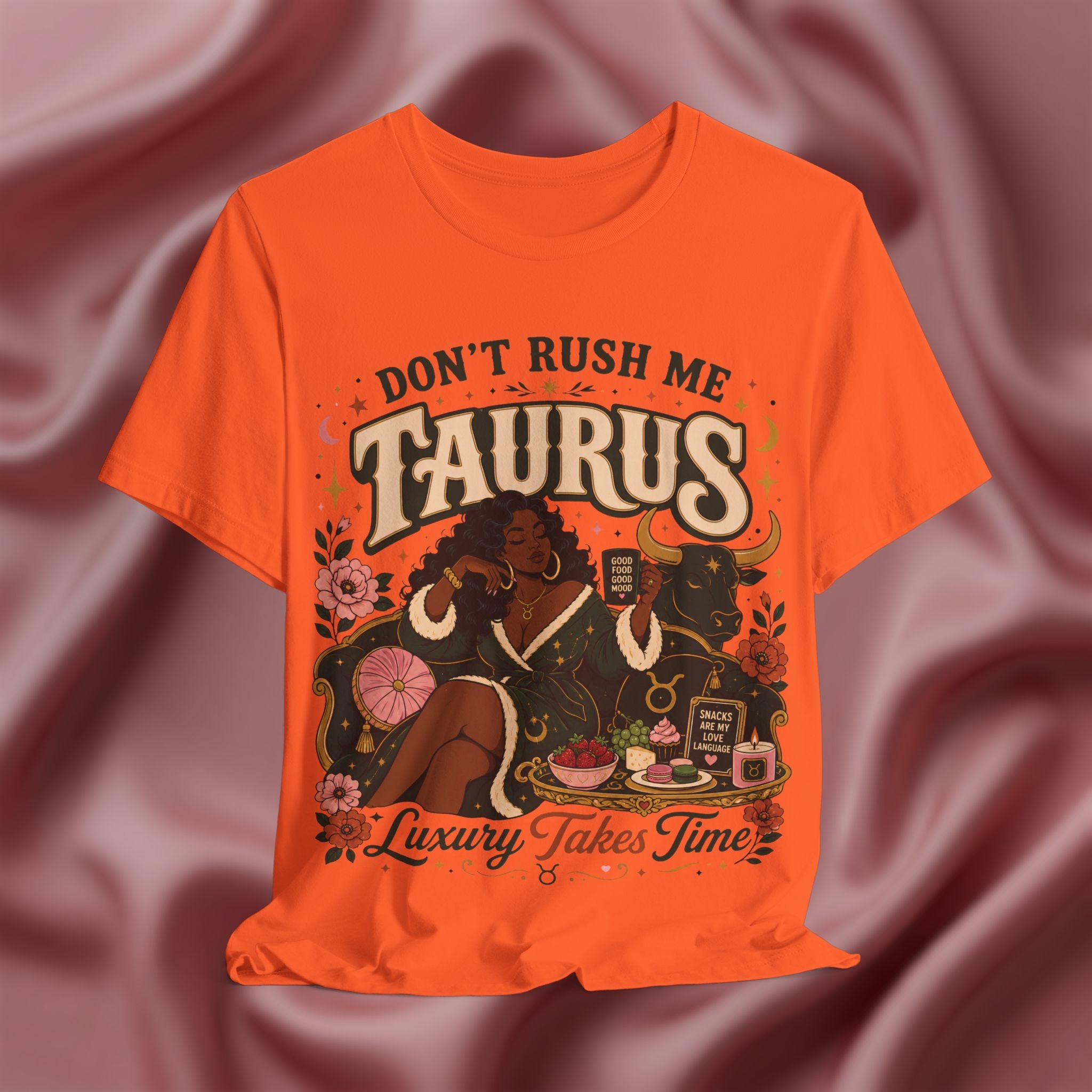 Orange t-shirt with 'Don't Rush Me, Taurus, Luxury Takes Time' design against a pink fabric background