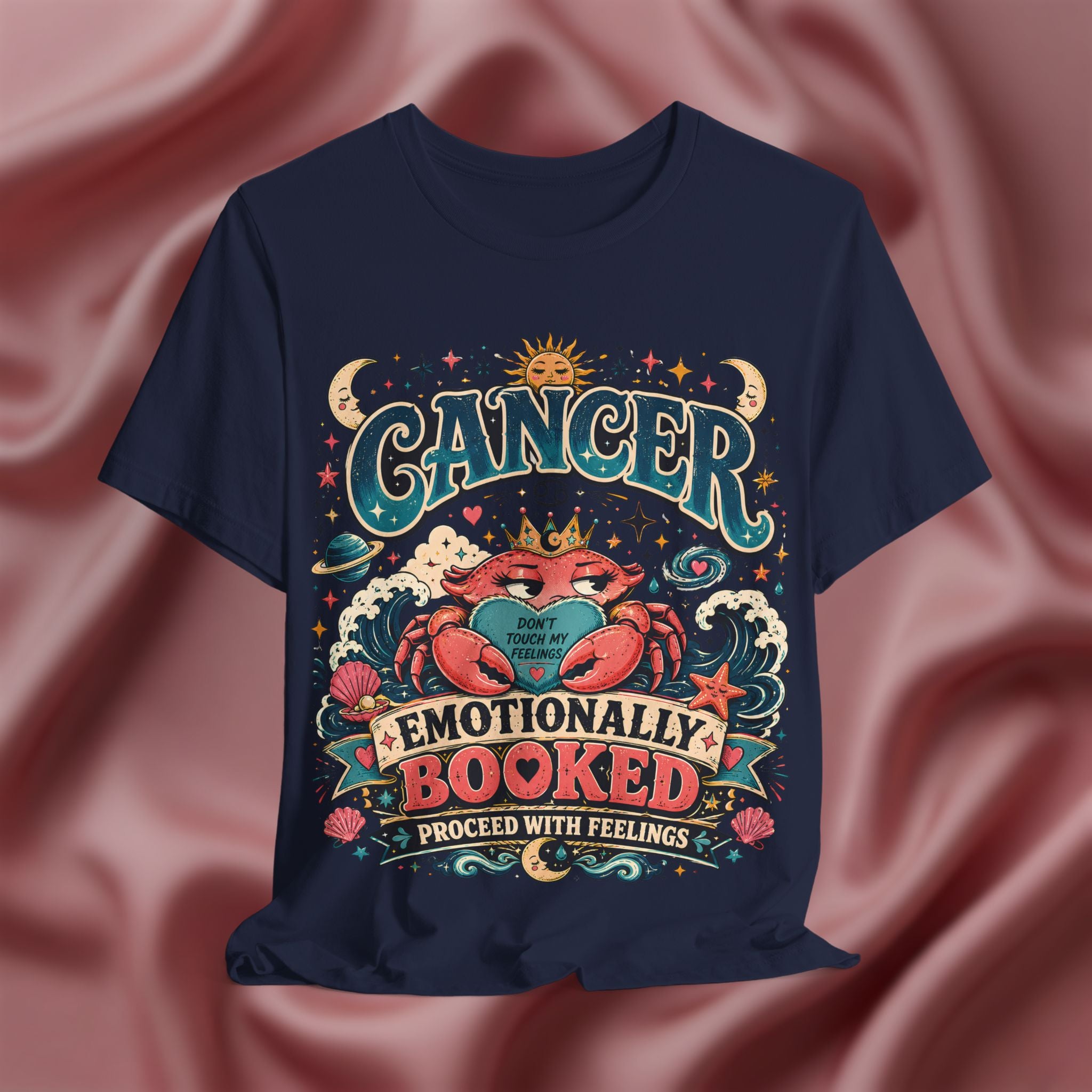 Navy blue t-shirt with colorful 'Cancer' zodiac design on a pink fabric background