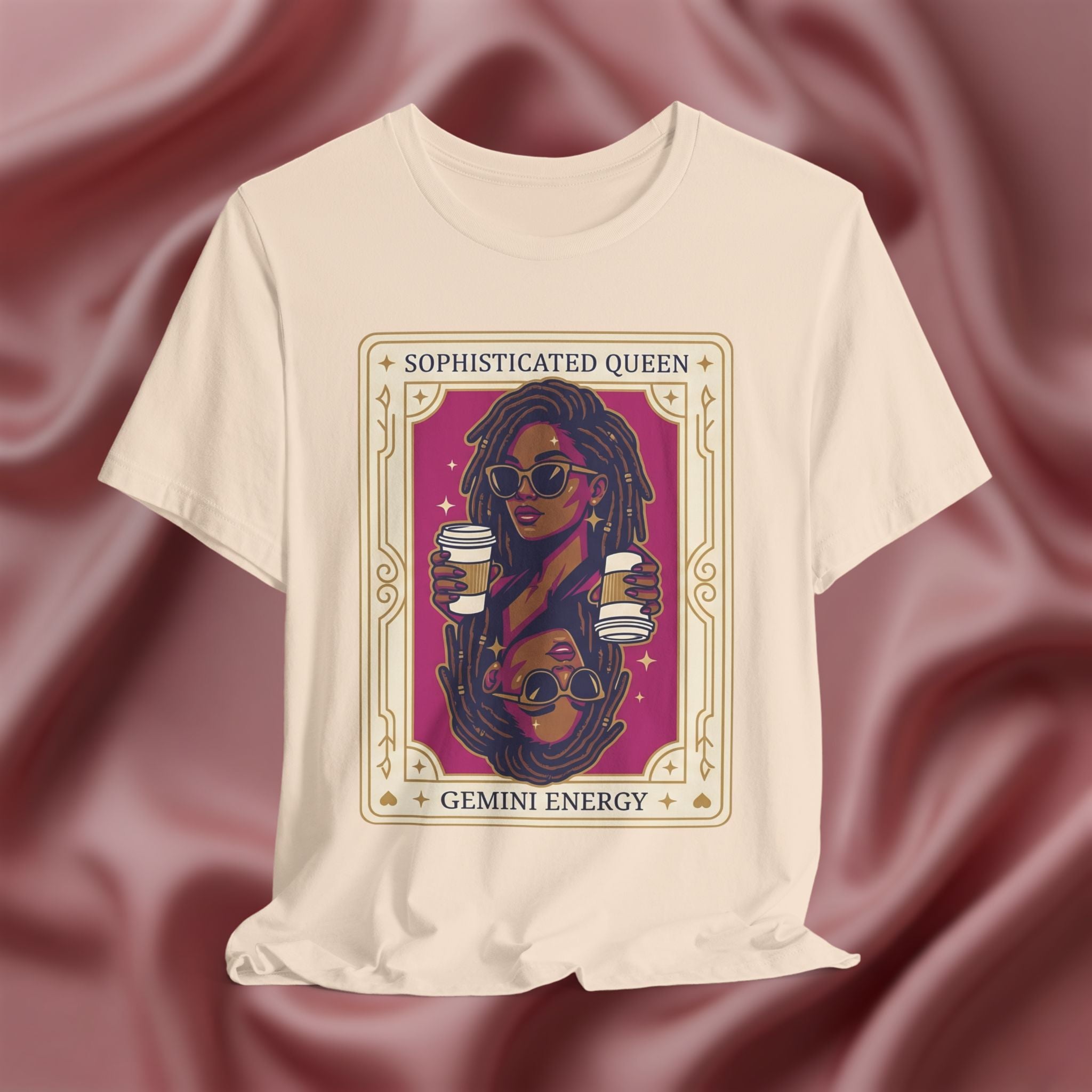 Sophisticated Queen Gemini Energy Beige t-shirt with a graphic design of a woman holding coffee cups on a maroon fabric background
