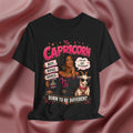 Black t-shirt with Capricorn zodiac design featuring a woman and goat on a pink fabric background