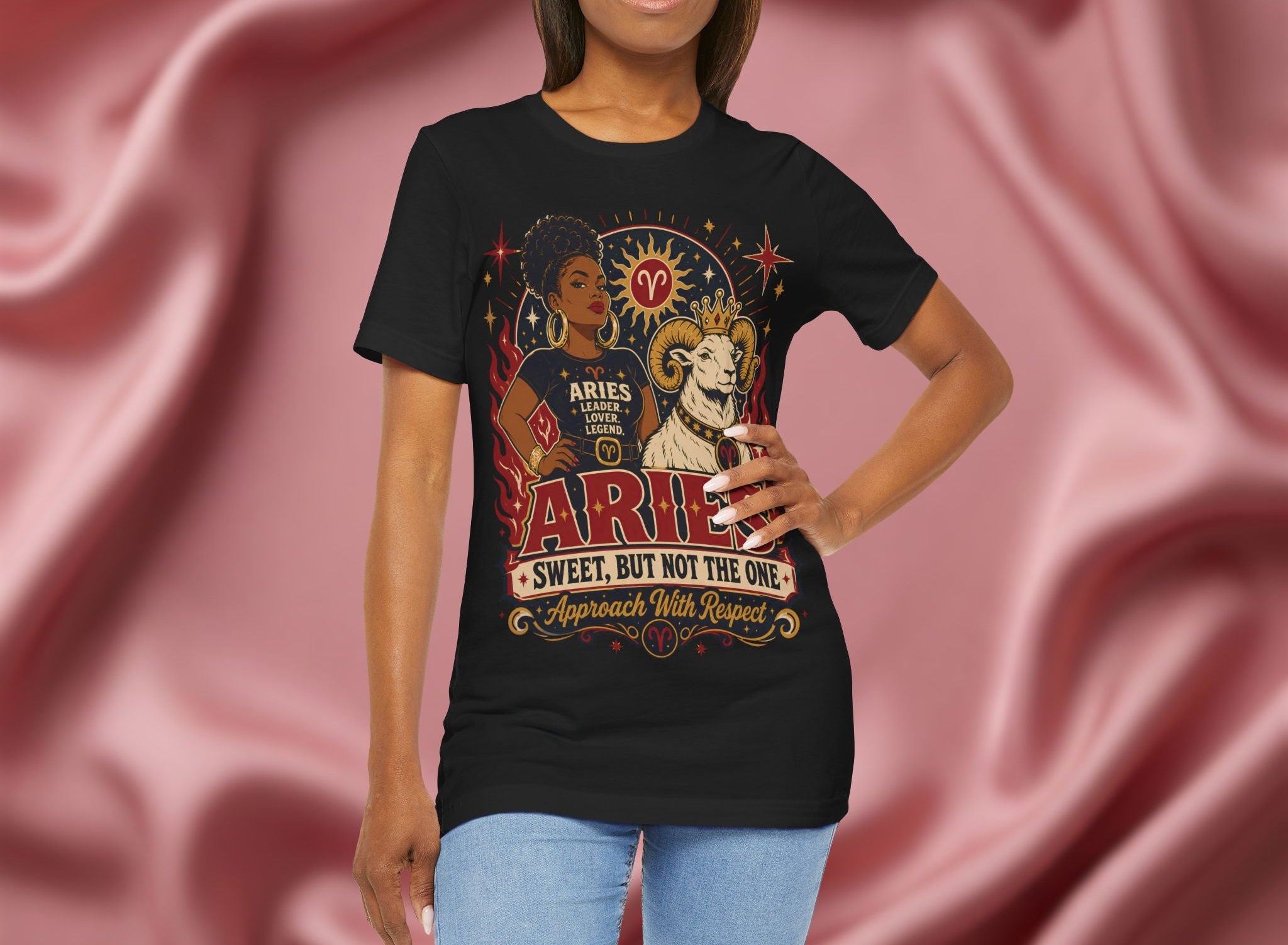 Woman wearing a black t-shirt with Aries zodiac design against a pink fabric background