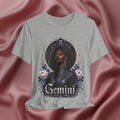 Gray t-shirt with a graphic design of a woman, flowers, and the word 'Gemini' on a pink fabric background.