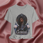 Gray t-shirt with a graphic design of a woman, flowers, and the word 'Gemini' on a pink fabric background.