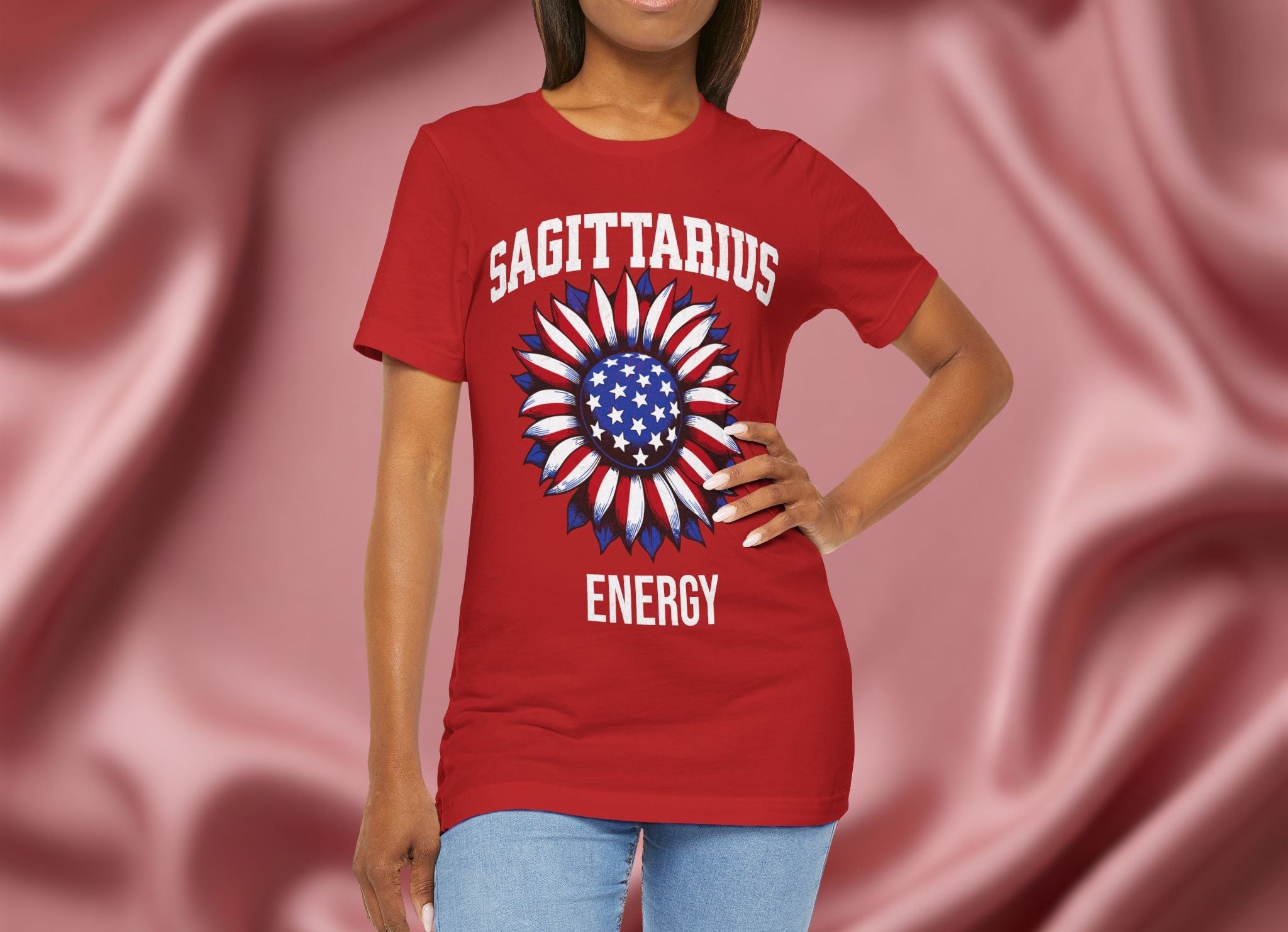 Person wearing a red t-shirt with American flag sunflower and 'SAGITTARIUS ENERGY' text on a textured pink background