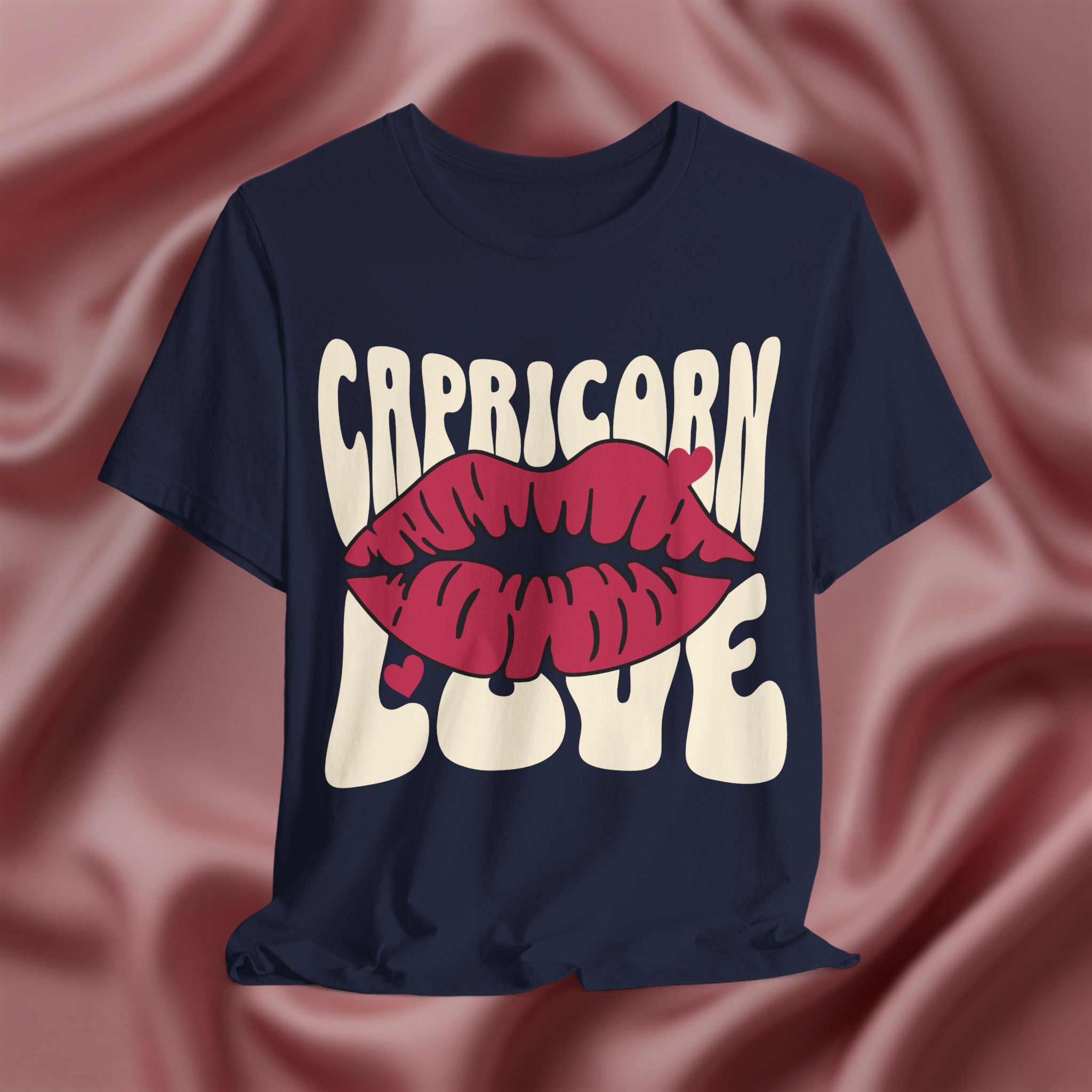 Navy blue t-shirt with 'Capricorn Love'  with hearts and lips graphic on a pink fabric background