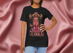 Person wearing a black t-shirt with Libra zodiac design on a pink fabric background