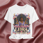 White t-shirt with Libra zodiac design on a maroon fabric background