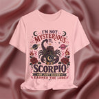 Pink t-shirt with Scorpio design and text on a maroon fabric background