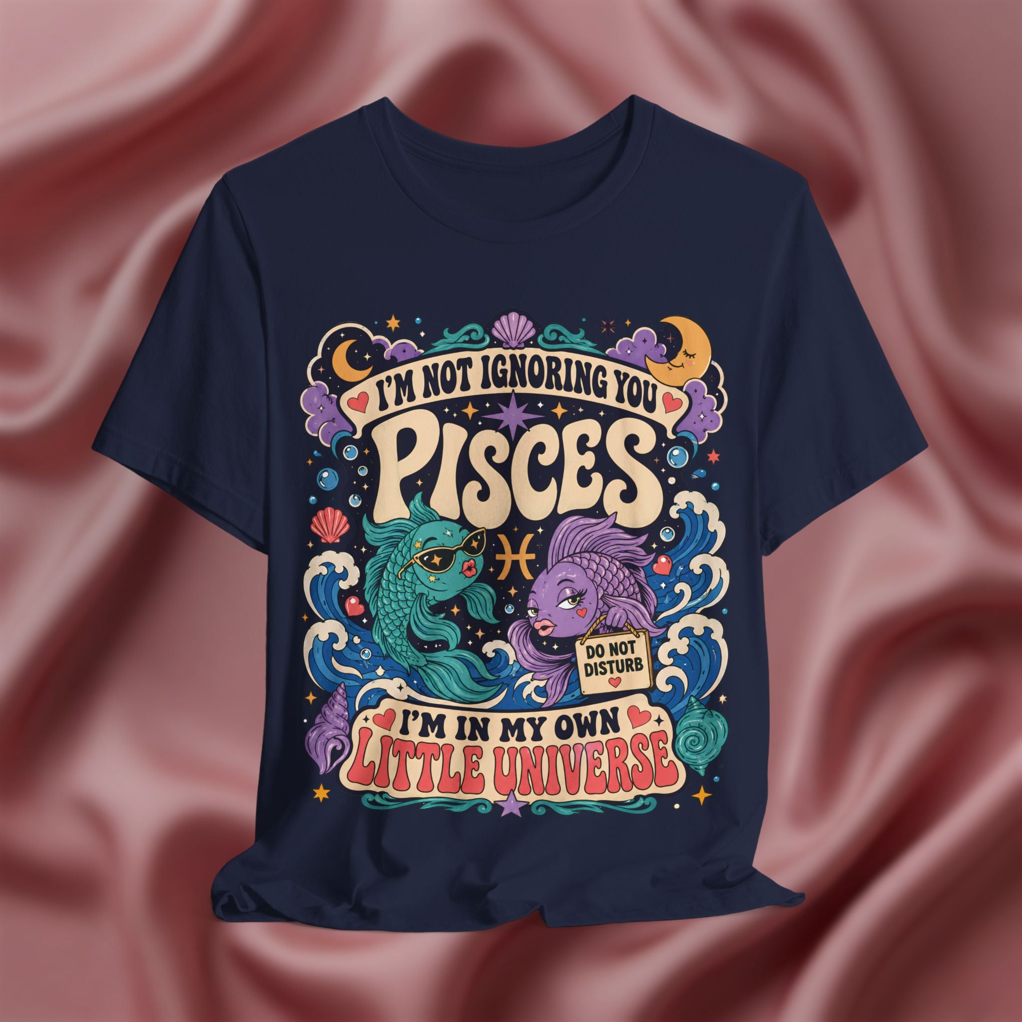 Navy blue t-shirt with colorful Pisces zodiac design on a pink fabric background