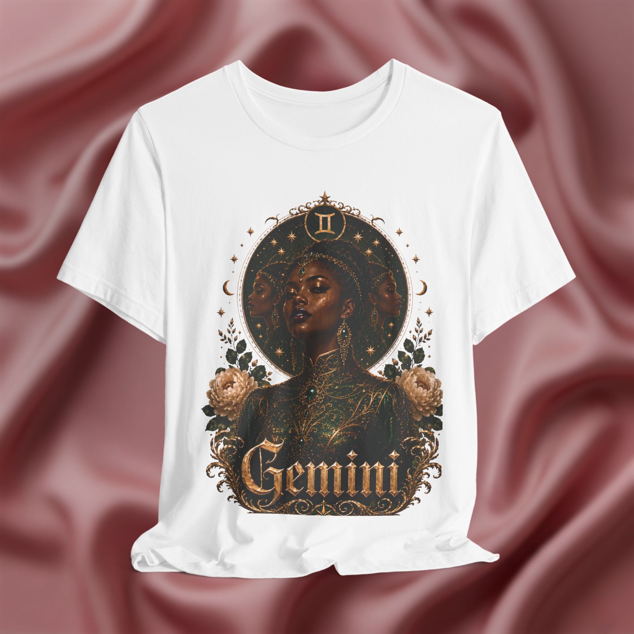 White t-shirt with a graphic design of a woman, flowers, and the word 'Gemini' on a pink fabric background.