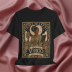 A black short-sleeve graphic t-shirt featuring an ornate vintage-style illustration of 'The Maiden Virgo' with celestial motifs, set against a draped dusty rose satin background.