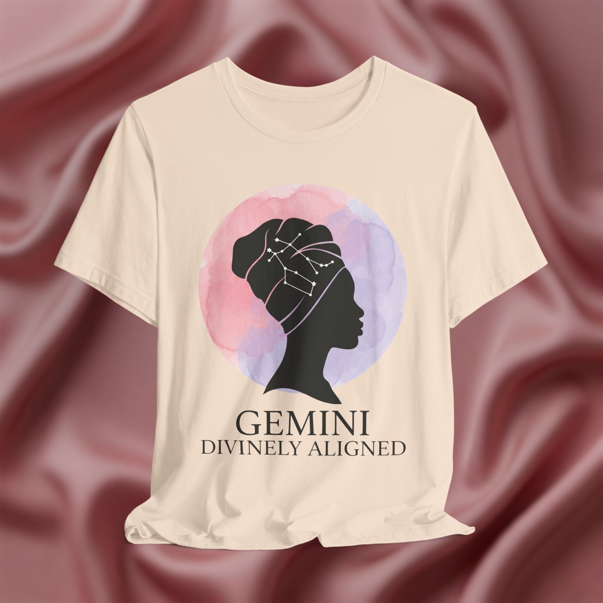 Soft cream t-shirt with a silhouette of a woman and 'Gemini Divinely Aligned' text on a pink fabric background