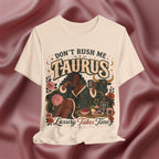 Soft cream T-shirt with 'Don't Rush Me, Taurus, Luxury Takes Time' design against a pink fabric background