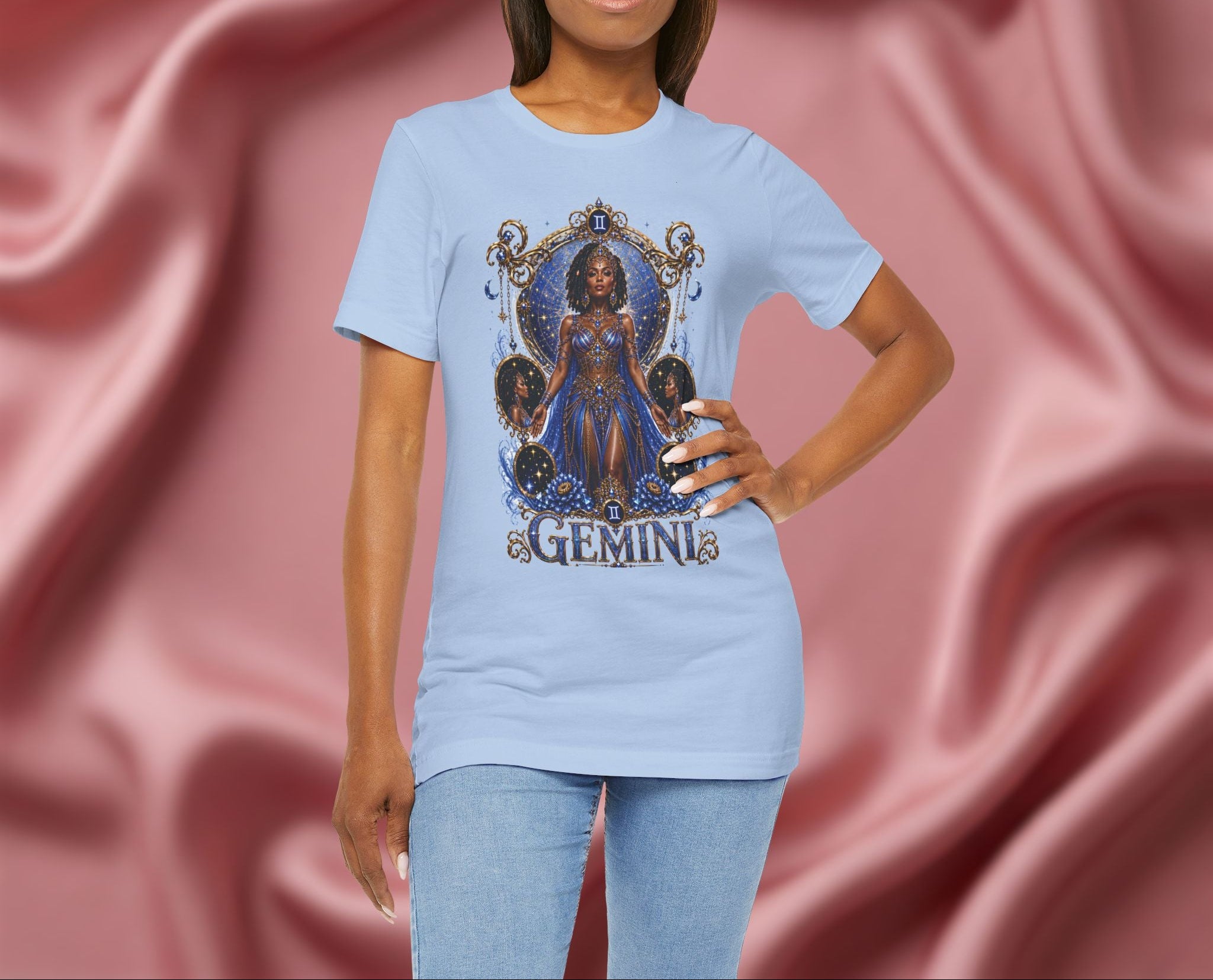 Woman wearing a light blue t-shirt with a graphic design and the word 'GEMINI' on a pink fabric background