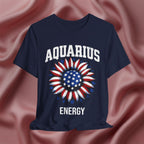 Navy blue t-shirt with American flag sunflower and 'AQUARIUS ENERGY' text on a textured pink background