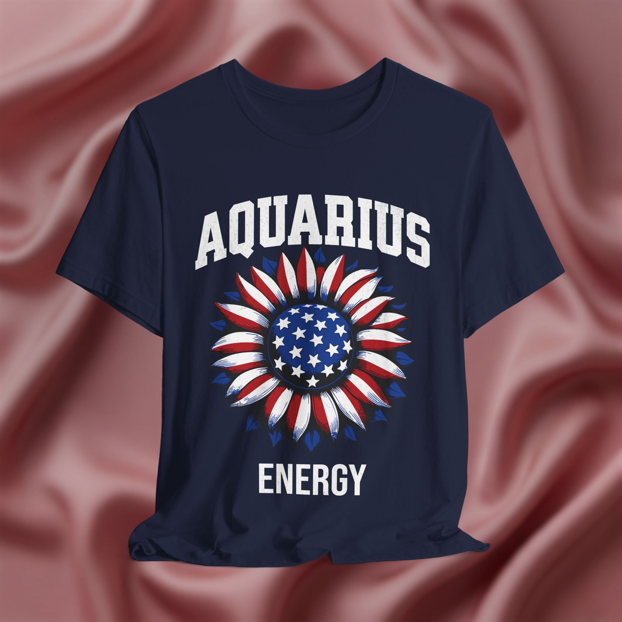 Navy blue t-shirt with American flag sunflower and 'AQUARIUS ENERGY' text on a textured pink background