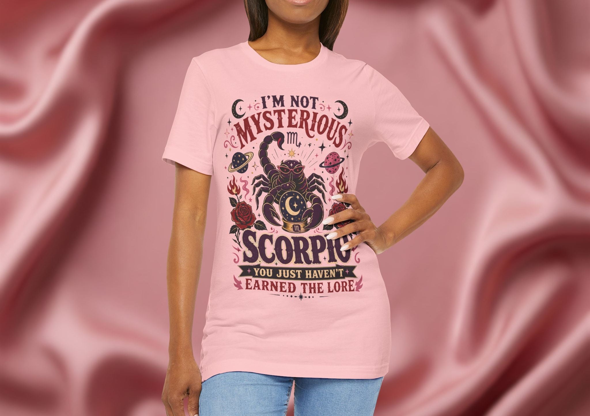 Person wearing a pink t-shirt with Scorpio design against a pink fabric background