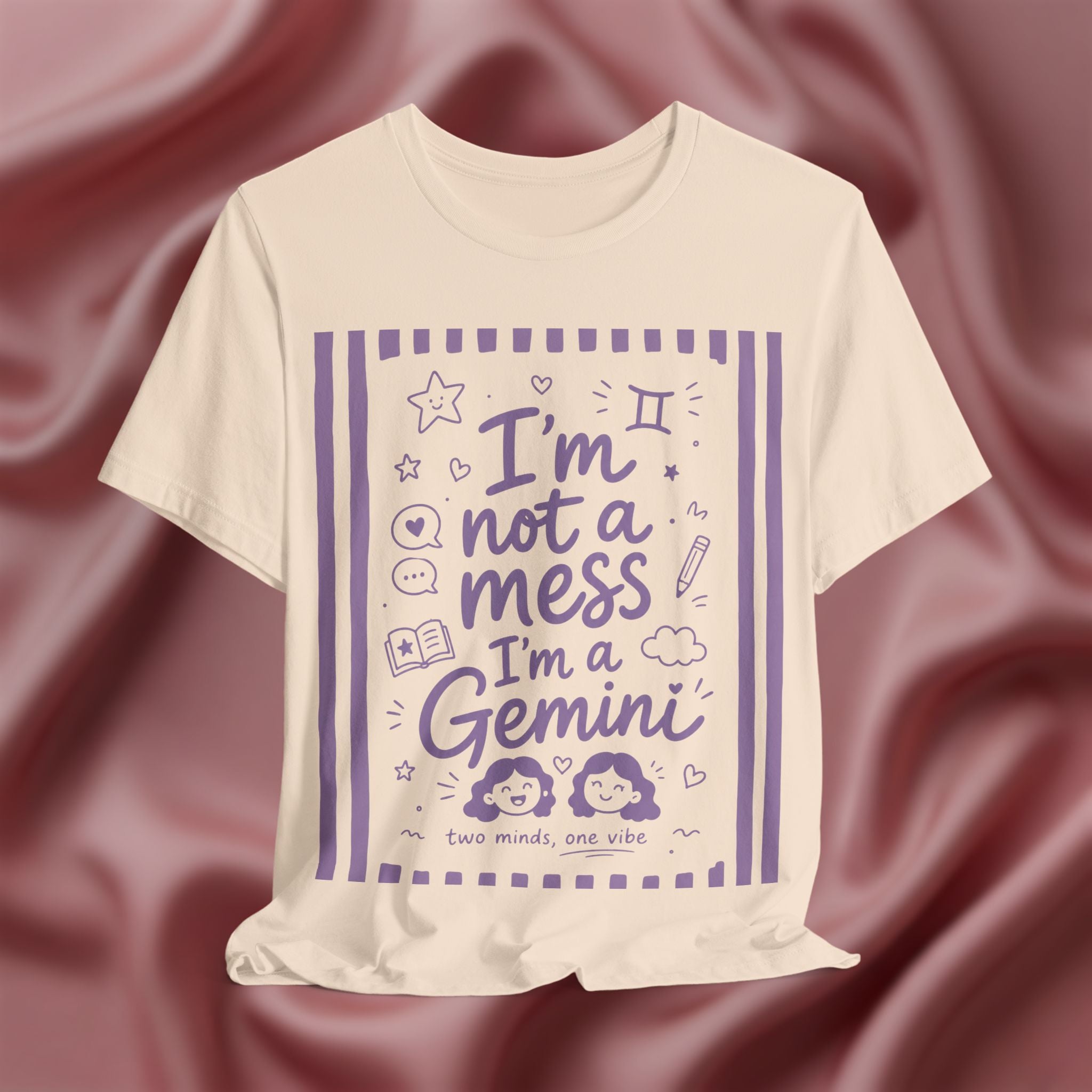 Soft cream t-shirt with purple text 'I'm not a mess I'm a Gemini and graphics on a pink fabric background