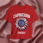 Red t-shirt with American flag sunflower and 'CAPRICORN ENERGY' text on a textured pink background