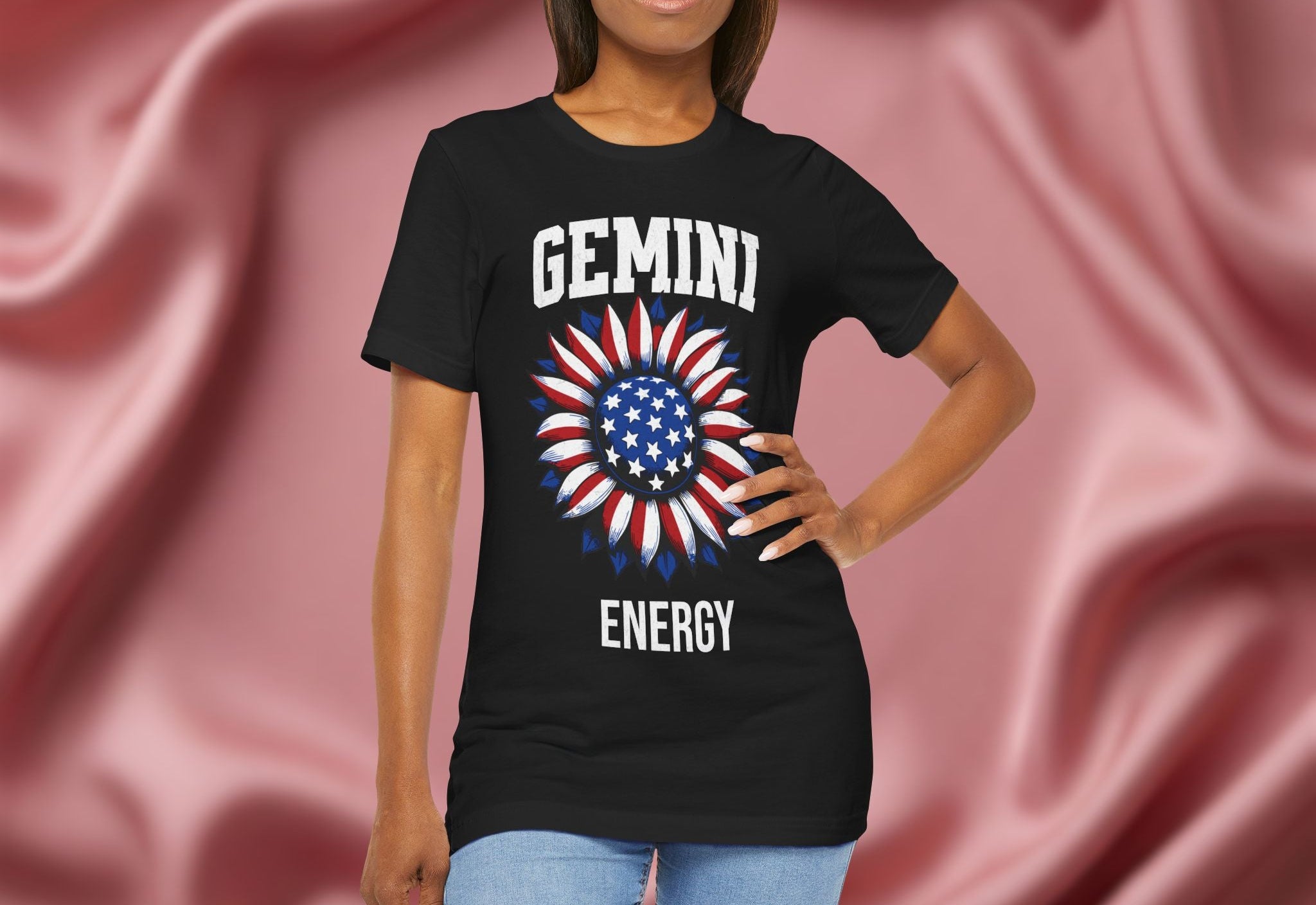 Person wearing a black t-shirt with American flag sunflower and 'GEMINI ENERGY' text on a textured pink background