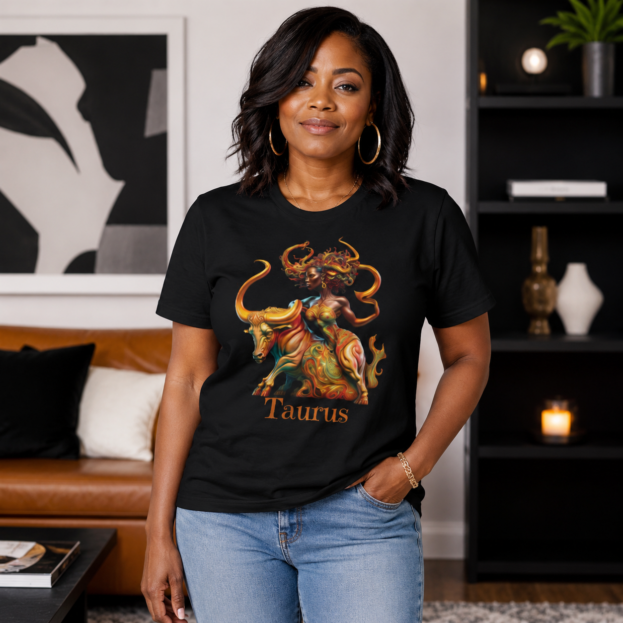 Woman wearing a black t-shirt with a Taurus graphic design featuring a bull and black woman  in a living room setting.