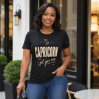 Woman wearing a black t-shirt with 'Capricorn Get you one' text in front of a clothing shop