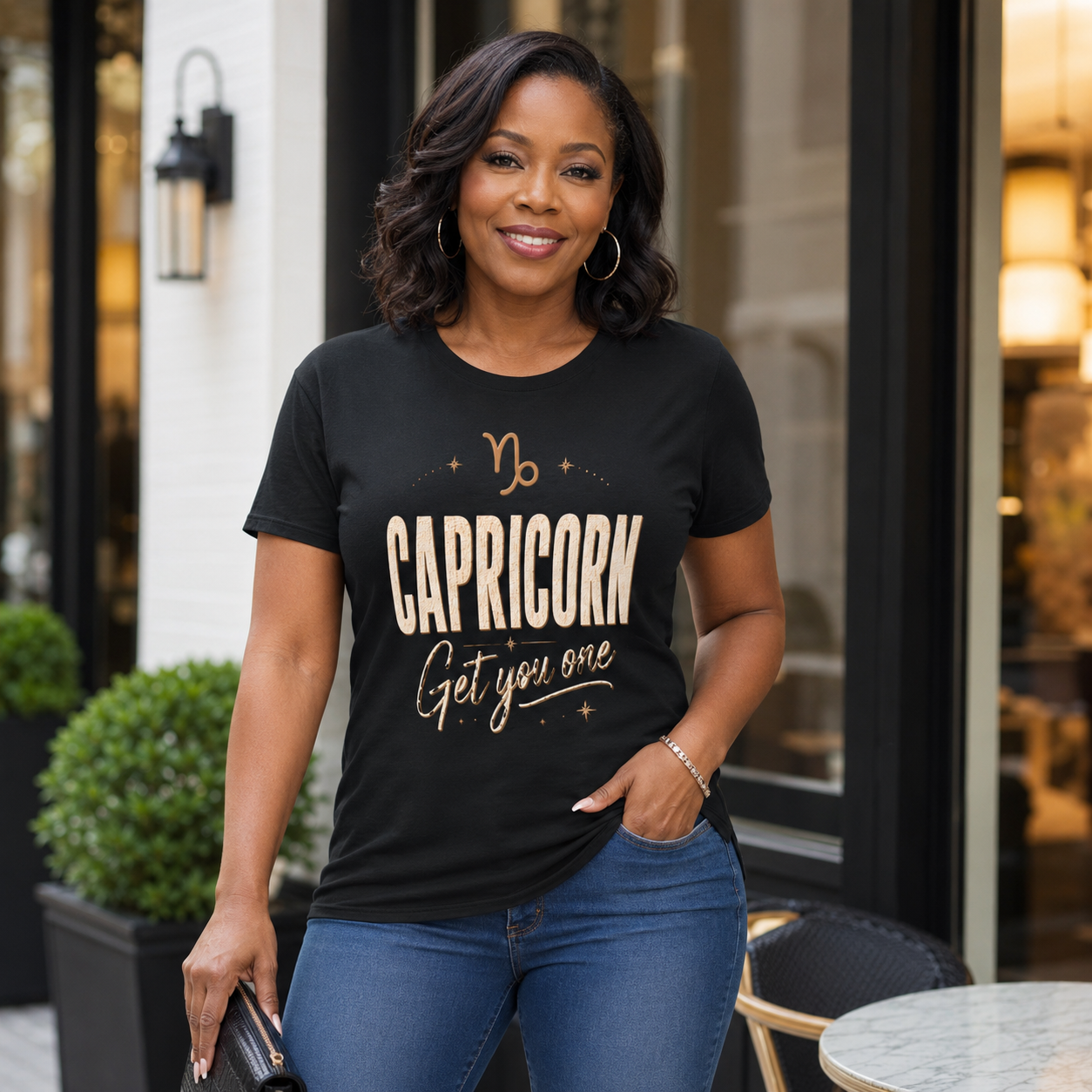 Woman wearing a black t-shirt with 'Capricorn Get you one' text in front of a clothing shop