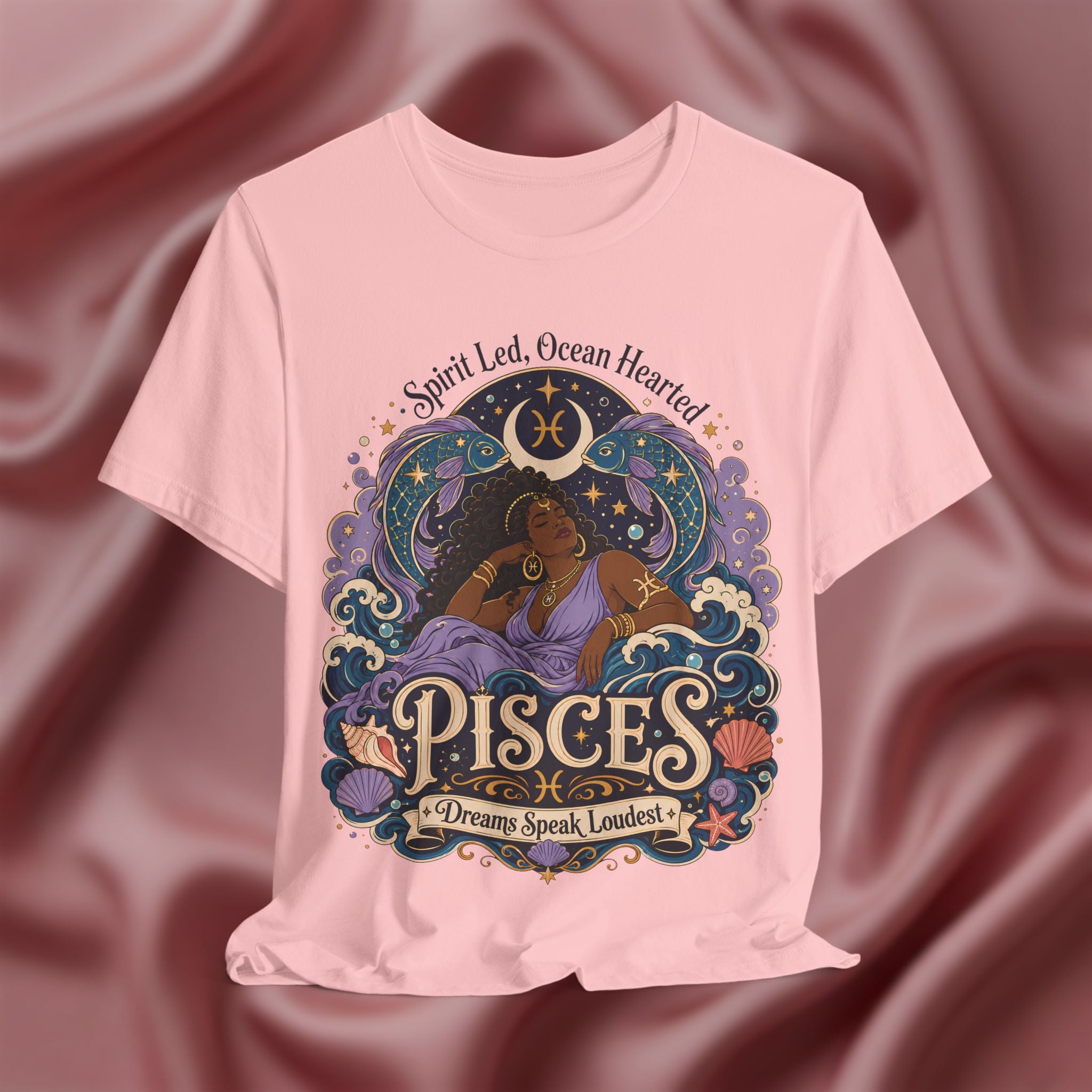 Pink t-shirt with Pisces zodiac design on a maroon fabric background