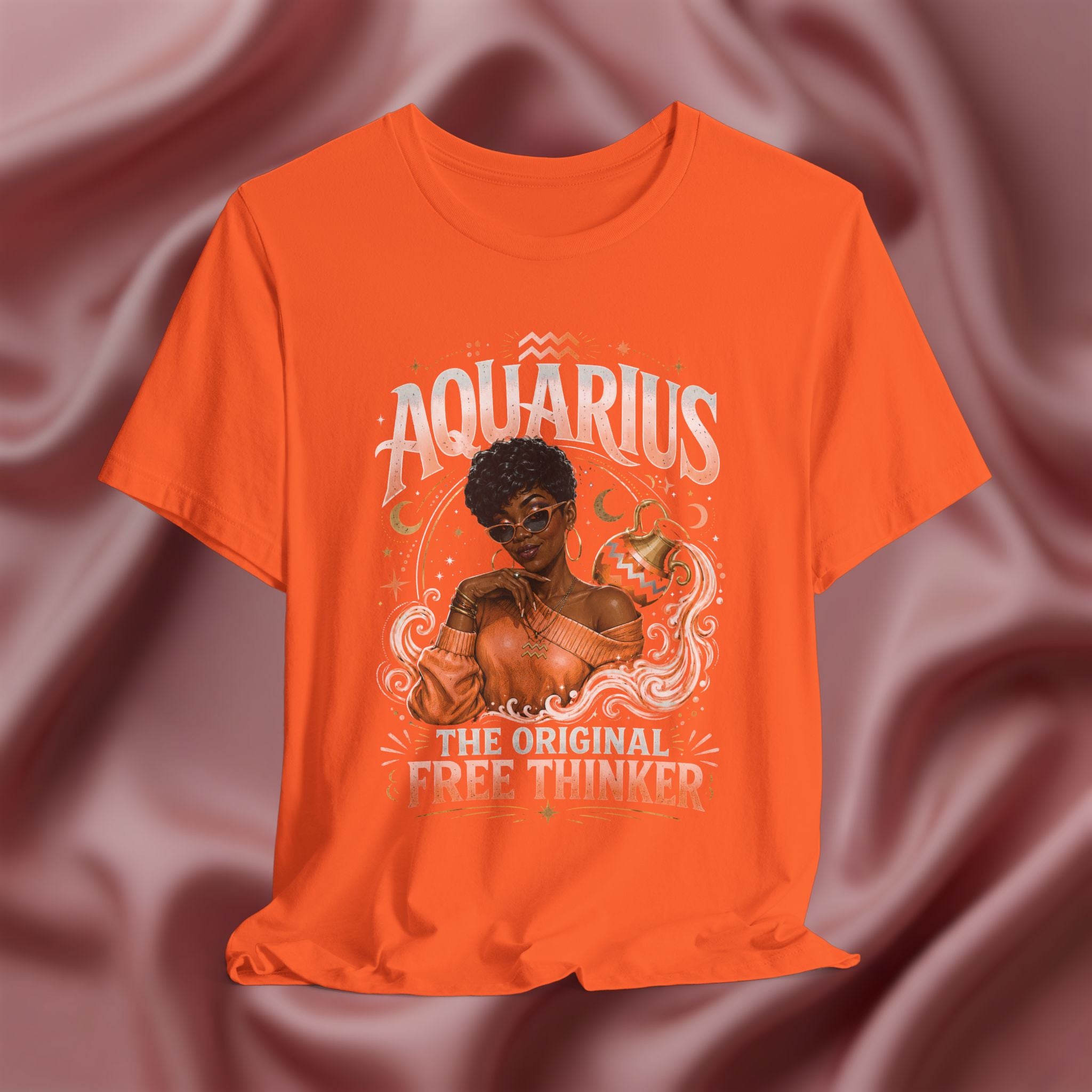 Orange t-shirt with Aquarius design featuring a black woman and text 'The original free thinker' on a pink fabric background