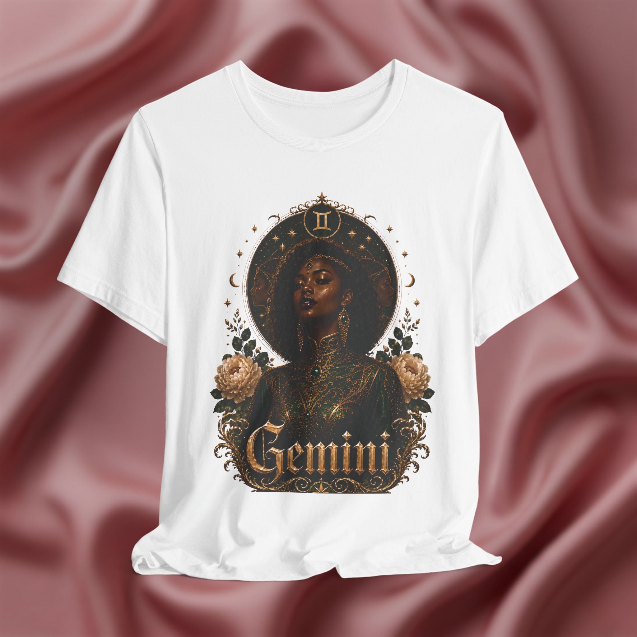 White t-shirt with 'Gemini' design featuring a black woman, roses, and astrological symbols on a maroon fabric background.